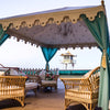 turquoise Arabian marquee tent with cane furniture with a lifeguard tower in the background on a beach