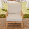 cane rattan sofa lounge with white cushions on a jute mat under a marquee