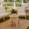 round rattan coffee table with white sofa and jute mat with floral arrangement