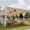 a beautiful exotic white Indian tent on a grassed property with rattan sofa lounges