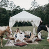 white bohemian tent in a field decorated with moroccan cushions and rugs with horses and brides