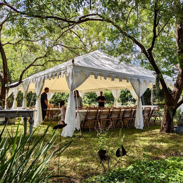 white bohemian wedding tent with tables and chairs in an outdoor setting