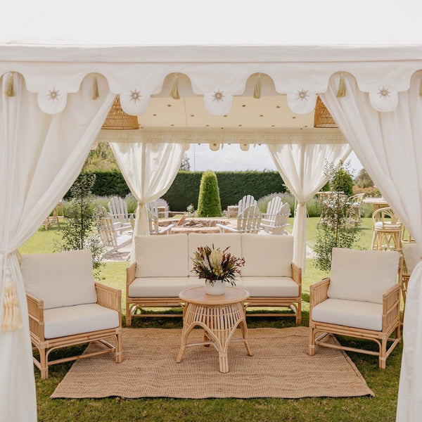 rattan sofa set with daybed and two single chairs with white cushions under a luxury marquee by Exotic Soirees