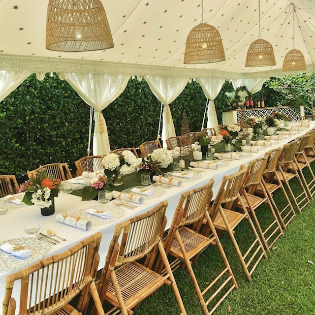 bamboo rattan chairs at a wedding table setting under a beautiful marquee with rattan lamps in the roof
