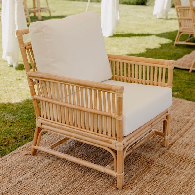 cane rattan sofa lounge with white cushions under a marquee