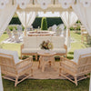 cane rattan sofa lounge with white cushions on a jute mat under a marquee from Exotic Soirees