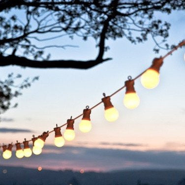 stunning festoon lights glowing in front of a backdrop of setting sun and mountains to hire from exotic soirees luxury marquees on the gold coast