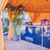 yellow octagonal marquee with a service bar setting in it decorated with palm trees and lights