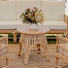 round rattan coffee table with white sofa and jute mat and floral arrangement