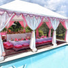 pink and white middle eastern marquee or garden tent next to a pool which is styled in pink for a children's party with low tables, grazing board, cushions